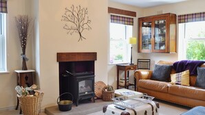 A cozy living room with a fireplace, a sofa, a coffee table, and a wicker basket. - A pretty stone cottage in the conservation village of Redmire. (Redmire near Leyburn)