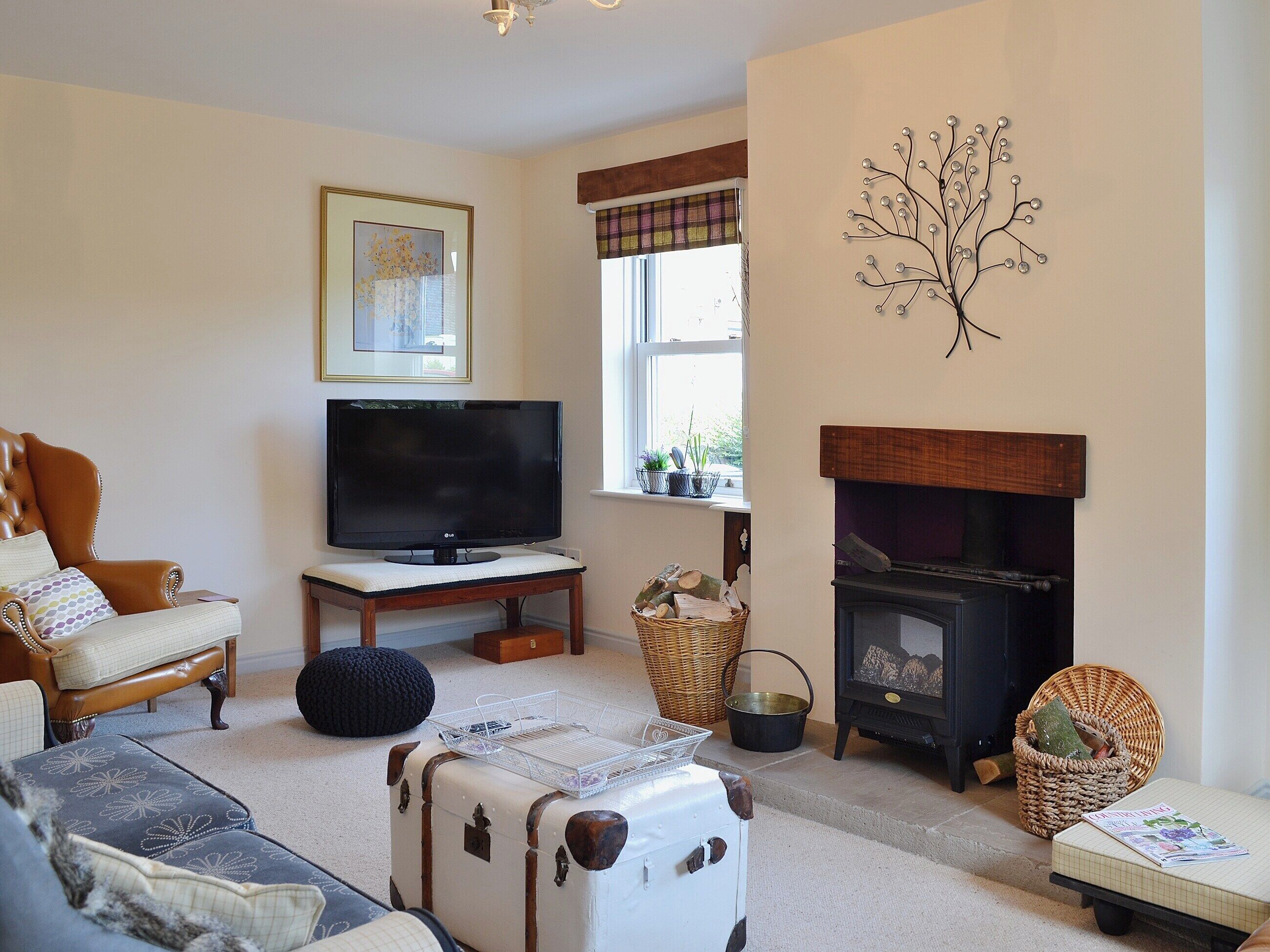 A living room with a television, a fireplace, a sofa, and a decorative tree wall piece.