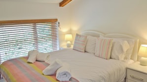 A neatly made bed with a striped blanket, white pillows, and a bedside lamp.