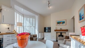 A modern living room with a white table, a sofa, and a TV. - 2 bedroom accommodation in Whitby (Whitby)
