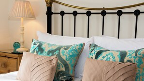 A neatly made bed with patterned pillows, a bedside table with a lamp, and a decorative item. - 2 bedroom accommodation in Whitby (Whitby)