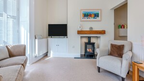 A living room with a fireplace, a television, and two sofas. - 2 bedroom accommodation in Whitby (Whitby)