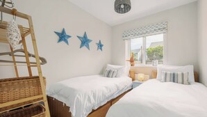 Een slaapkamer met twee bedden, een houten trap en drie blauwe sterdecoraties aan de muur.