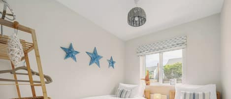 A bedroom with two beds, a wooden ladder, and three blue star decorations on the wall.