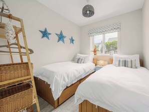 A bedroom with two beds, a wooden ladder, and three blue star decorations on the wall.