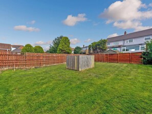 A backyard with a wooden fence, a shed, and a lawn.