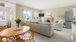 Een gezellige woonkamer met een bank, een eettafel met stoelen en een open haard.