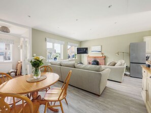 A cozy living room with a sofa, a dining table with chairs, and a fireplace.