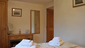 A hotel room with a bed, a desk, a chair, a mirror, and a door. - Explore North Yorkshire from this cosy, dog-friendly former stable near Thirsk. (South Kilvington near Thirsk)