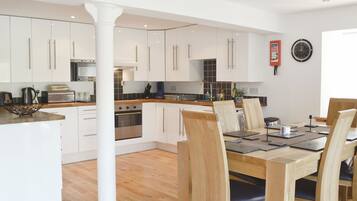 A modern kitchen with white cabinets, a central island, and a dining area with wooden chairs and a table.