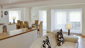 Un vaste espace de vie comprenant un canapé, une table à manger avec des chaises, un comptoir de cuisine et une vue dégagée grâce à de grandes fenêtres.