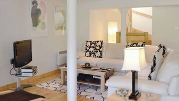 A modern living room with a flat-screen TV, a white sofa, a coffee table, and a lamp.