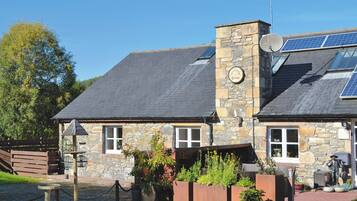 A stone building with a sloped roof, solar panels, and a sign that reads 'The Old Grange.'