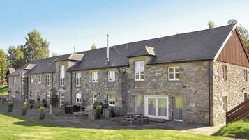 A stone building with multiple windows and a sloped roof.