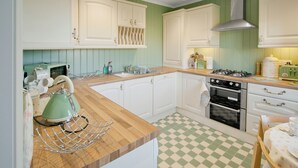 A kitchen with white cabinets, a green checkered floor, a vintage toaster, and a kettle. - 2 bedroom accommodation in Clachan near Tarbert (Clachan near Tarbert)