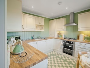 A kitchen with white cabinets, a green checkered floor, a vintage toaster, and a kettle.