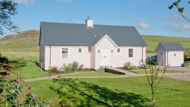 A two-story house with a grey roof, a white door, and a small attached garage. - 2 bedroom accommodation in Clachan near Tarbert (Clachan near Tarbert)