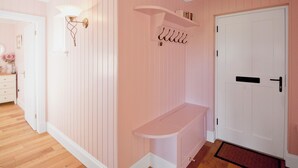 A room with pink walls, a white door, a bench, and a wall-mounted light fixture. - 2 bedroom accommodation in Clachan near Tarbert (Clachan near Tarbert)