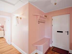 A room with pink walls, a white door, a bench, and a wall-mounted light fixture.