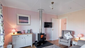 A cozy living room with a fireplace, a sofa, a chair, a TV, and a cabinet. - 2 bedroom accommodation in Clachan near Tarbert (Clachan near Tarbert)