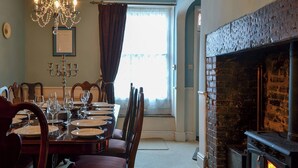 A dining room with a fireplace, a chandelier, and a window with curtains. - 4 bedroom accommodation in Cleobury Mortimer, near Ludlow (Cleobury Mortimer, near Ludlow)