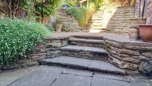 A stone staircase leading up to a wooden door, surrounded by lush greenery and potted plants. - 4 bedroom accommodation in Cleobury Mortimer, near Ludlow (Cleobury Mortimer, near Ludlow)