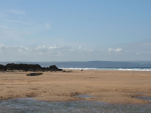 Ein Strand mit klarem Himmel, Felsformationen und ruhiger See.