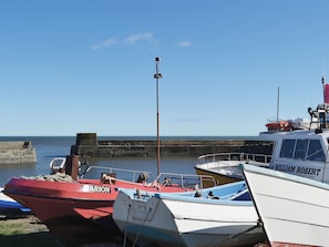 Un port où plusieurs bateaux sont amarrés, dont un bateau rouge appelé « ARION » et un bateau blanc appelé « WILLIAM ROBERT ».