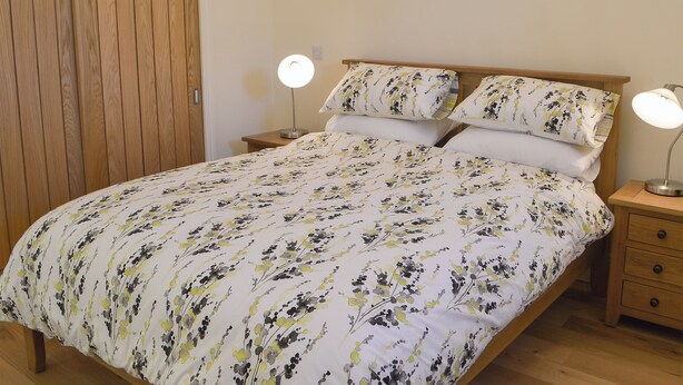 Ein Schlafzimmer mit einem Bett, zwei Nachttischen, einem Nachtschränkchen und einem Holzschrank.