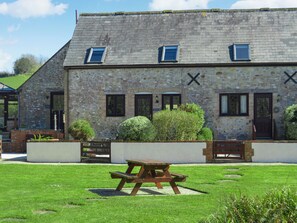 A stone building with a sloped roof, multiple windows, and a picnic table in the foreground. - 3 bedroom accommodation in Lyme Regis (Lyme Regis)