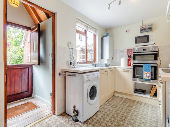 A compact kitchen with a washing machine, a microwave, and a sink.