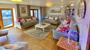 Ein Wohnzimmer mit zwei Sofas, einem Couchtisch und einem mit Lichtern geschmückten Baum.