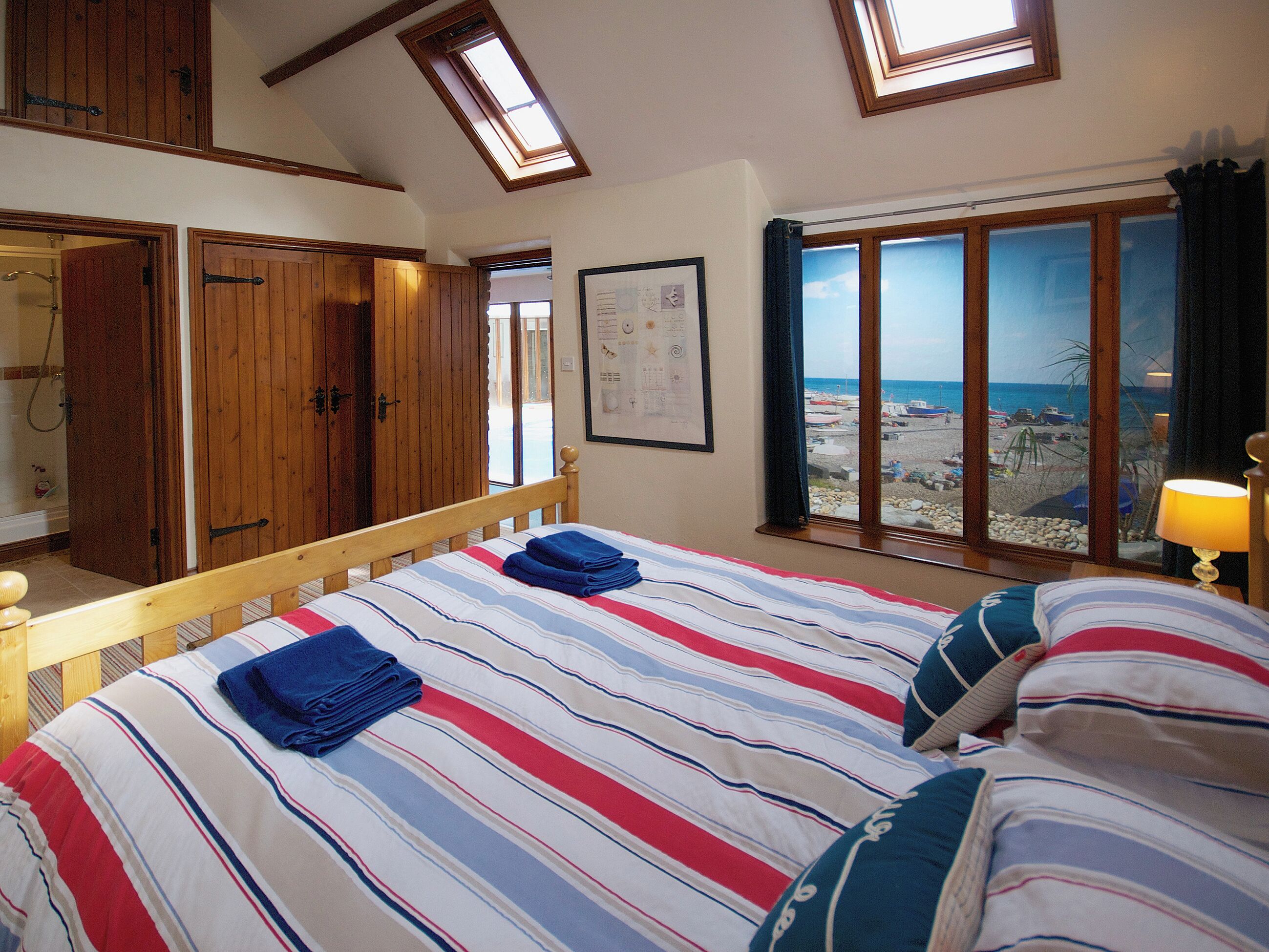Een slaapkamer met een bed, een houten garderobe en uitzicht op het strand.
