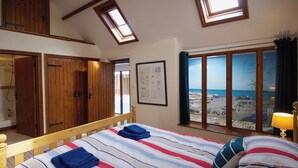 Ein Schlafzimmer mit Bett, Holzschrank und Blick auf den Strand.