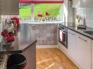 A modern kitchen with a large window, a built-in oven, and a countertop with mugs. - 3 bedroom accommodation in Ballantrae, near Girvan (Ballantrae, near Girvan)