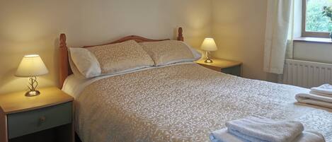 A neatly made bed with a patterned bedspread, two bedside lamps, and a framed artwork on the wall.
