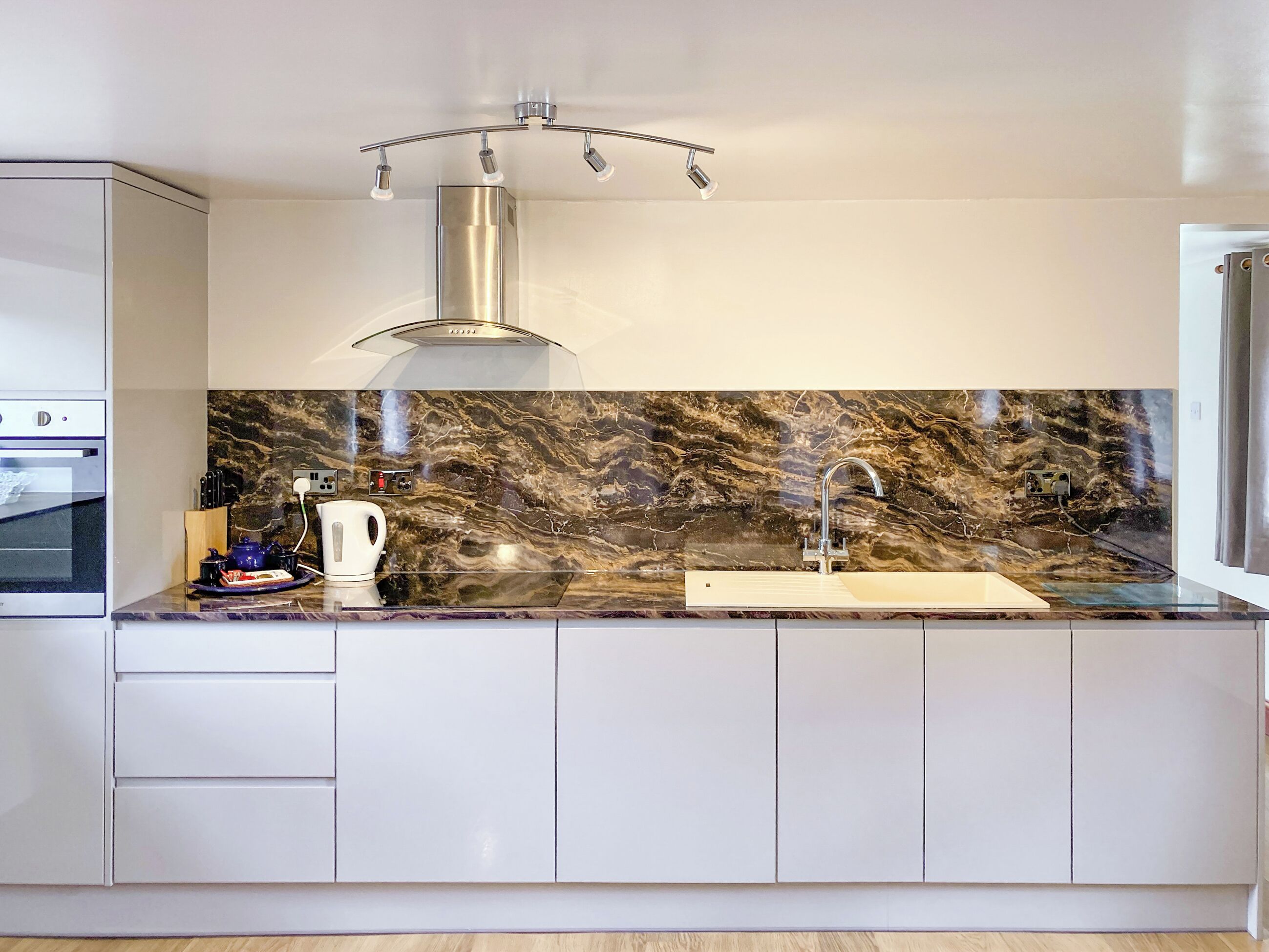 A modern kitchen with a marble backsplash, stainless steel appliances, and a built-in sink.
