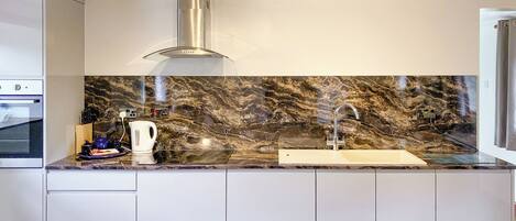 A modern kitchen with a marble backsplash, stainless steel appliances, and a built-in sink.