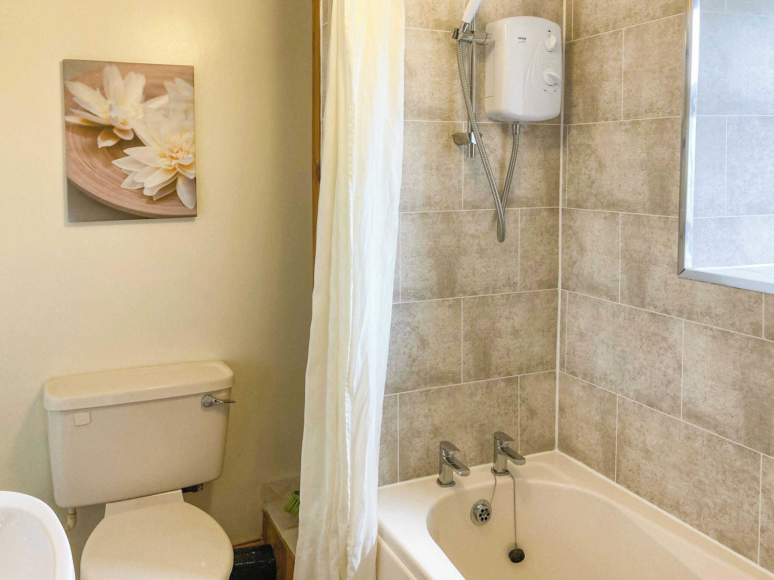 A bathroom with a toilet, a shower, and a sink.