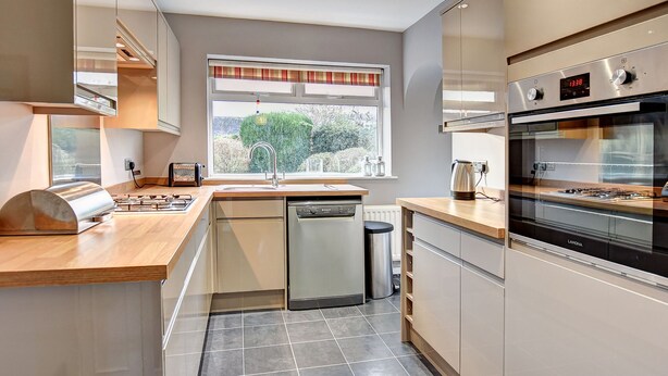 Een moderne keuken met een inbouwvaatwasser, een gasfornuis en een oven.