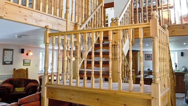 Un escalier en bois, doté d’une rampe, qui mène à un niveau supérieur.
