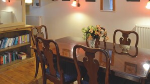 Un coin repas avec une table en bois, des chaises et une bibliothèque remplie de livres.