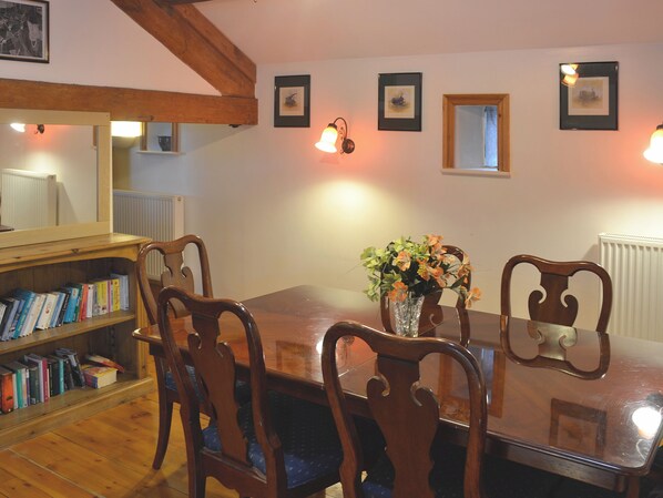A dining area with a wooden table, chairs, and a bookshelf filled with books.