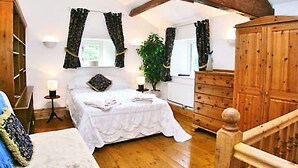 Une chambre à coucher avec un lit en bois, une commode, une table de chevet, une plante en pot et un escalier.