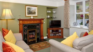 Una sala de estar con chimenea, sofá, televisión y una estantería.
