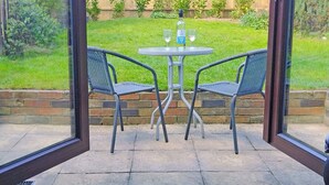 An outdoor patio with two chairs and a table, a bottle of wine, and two glasses. - 2 bedroom accommodation in Hemingby, near Horncastle (Hemingby, near Horncastle)