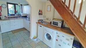 A compact kitchen with a washing machine, microwave, and wooden staircase. - 2 bedroom accommodation in Hemingby, near Horncastle (Hemingby, near Horncastle)