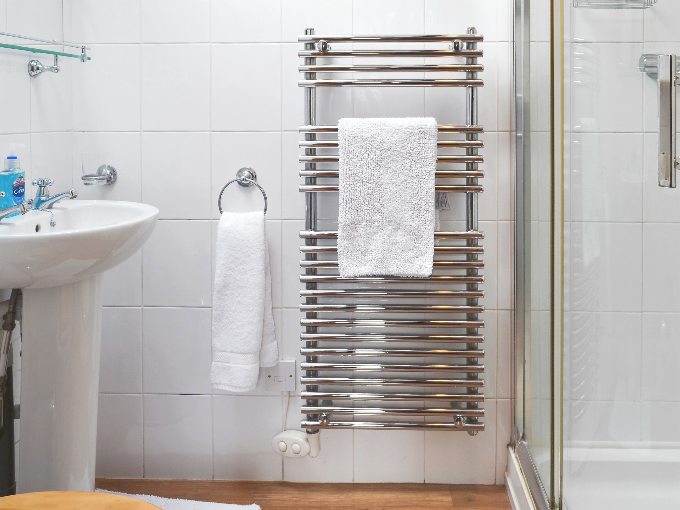 Ein Badezimmer mit einem weißen Waschbecken, einer Duschkabine aus Glas und einem Handtuchhalter mit einem weißen Handtuch.