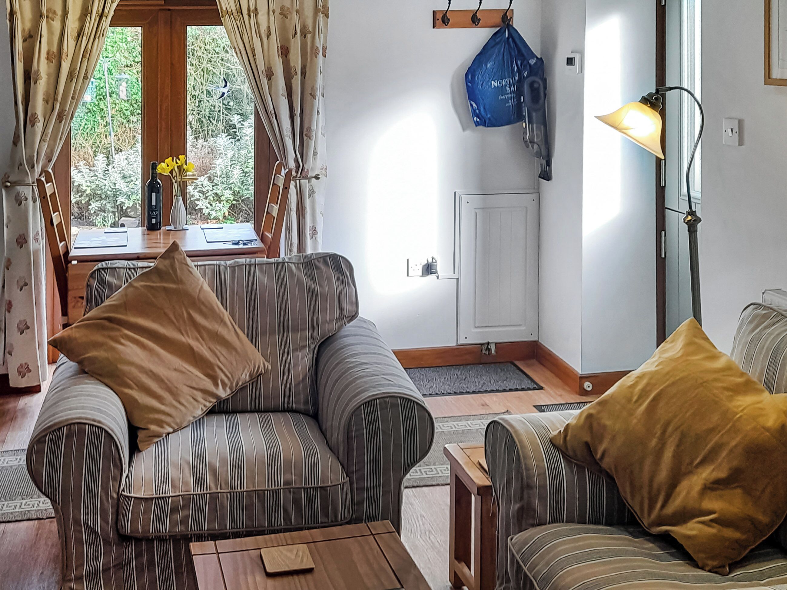 Ein gemütliches Wohnzimmer mit gestreiften Sofas, einem Holztisch und einer Lampe.