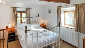 Une chambre à coucher avec un lit à baldaquin, un banc en bois, une table de chevet et une fenêtre avec des rideaux.